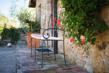 relaxing place with bench, flower, brick house in tuscany, italy