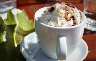 Cup of coffee with cream and autumn leaf