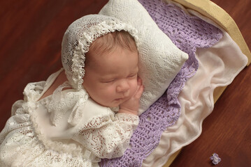 Fototapeta na wymiar Beautiful newborn baby girl gently sleeping on a purple blanket