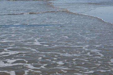 a wave rolled over the sandy shore
