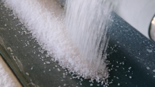 Natural salt is poured along a conveyor belt at a factory