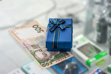 The gift box lies on the table with the Ukrainian currency hryvnia. Shopping concept in Ukraine