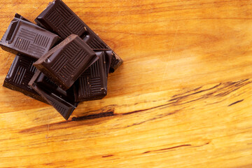 Dark chocolate pieces isolated on wooden background