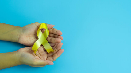 Hands hold gold ribbon, Sarcoma Awareness, Bone cancer, childhood cancer awareness, World Suicide...