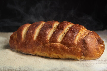 Freshly baked loaf of bread on a coarse gray cloth sprinkled with flour