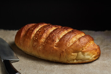 Bread loaf on a coarse gray cloth and a knife for cutting bread