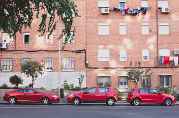 Fototapeta na wymiar Three red cars are parked on a city street. City landscape with cars. Madrid, Spain.