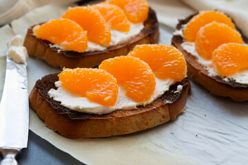 Delicious toast with sweet tangerine on black wood background
