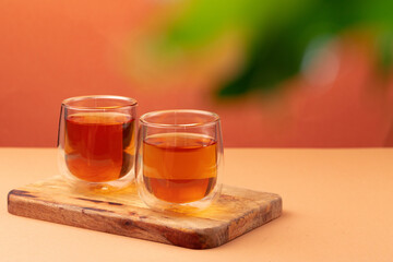 Two glass cups of black tea on beige table