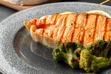 Grilled salmon steak with broccoli on grey plate