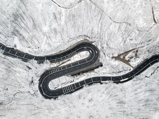 Foto op Aluminium Winding road through the forest, from high mountain pass, in winter time. Aerial view by drone. Romania © Rafaila Gheorghita