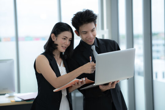 Asian business woman point at laptop screen work together with boss manager