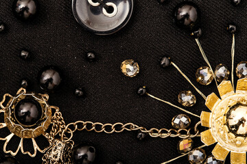 Black beads, golden flowers and chain on fabric