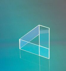 Penrose "impossible" triangle made with glass microscope slides illuminated edges on a coloured background