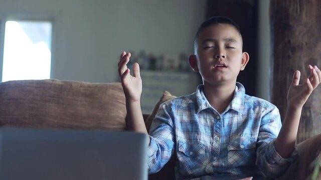 Boy raise up hands praying in front computer laptop, Online church in home, Home church during quarantine coronavirus Covid-19, Religion concept.