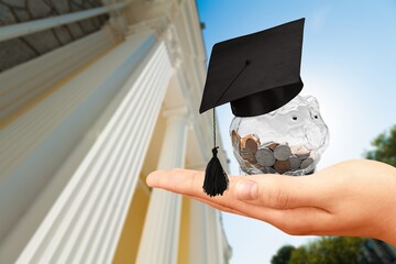 Graduation hat on a glass jar with money in hand
