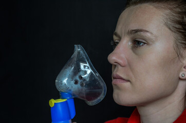 Woman breathing into mask while making inhalation on black background	