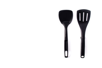 Black plastic kitchen spatula and spoon isolated on white background.Copy space	