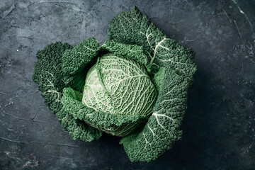 Fototapeta premium Raw green cabbage texture. Organic savoy cabbage on dark background. Top view. Copy space. Vegan and vegetarian diet concept