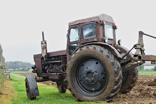 Old brown Soviet diesel wheeled tractor close up with on the field, soil cultivation on an autumn day, rural agriculture farming landscape