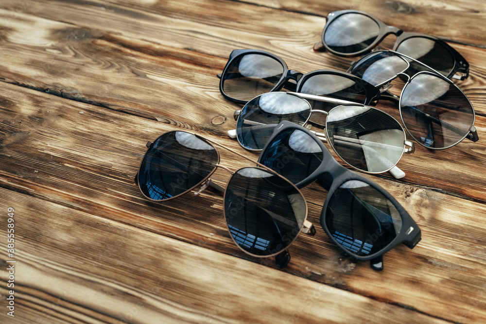 Wall mural set of dark sunglasses on brown wooden surface