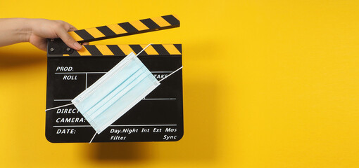 Hand is holding black clapper board or movie slate with face mask. it use in video production and...