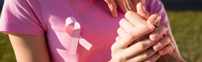Panoramic shot of woman with sign of breast cancer awareness holding hand