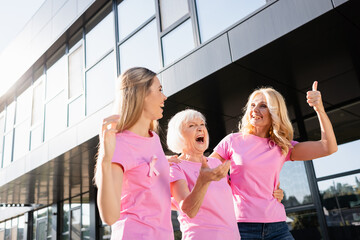 Three women hugging and laughing outdoors, concept of breast cancer