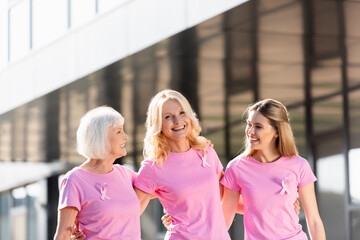 Selective focus of three women with ribbons of breast cancer awareness outdoors