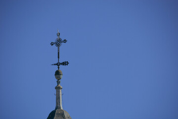 Fototapeta na wymiar Detalle de cruz de un campanario de iglesia neoclásica con cielo azu