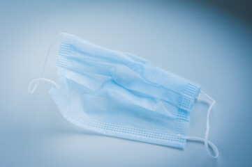 Used medical protective mask on a blue background