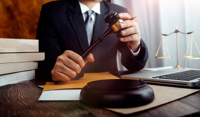 Justice and law concept.Male judge in a courtroom with the gavel, working with, computer and...