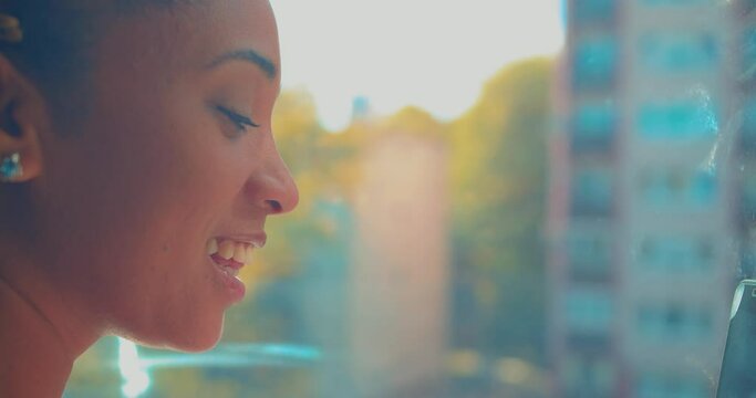 Profile Happy Mixed Race Girl by Windown Talking During Video Call With Friend. Social Distancing and Networking Concept, Close Up Full Frame