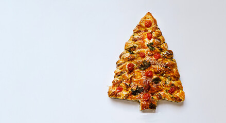 Homemade Christmas cake in the shape of a Christmas tree on a white background. Fresh pastries with tomatoes and cheese decorated with greenery.