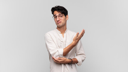 young handsome man feeling confused and clueless, wondering about a doubtful explanation or thought