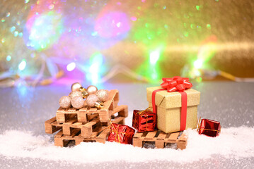 Christmas gifts on the wooden pallets in the snow, with color bokeh, christmas decorations.