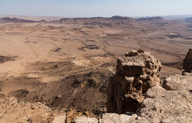 dizzying vista from the western rim of the makhtesh ramon crater in israel showing the nahal wadi ramon stream bed and other geological features
