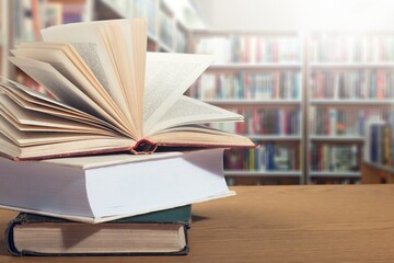 Open book on stack of books with library background.