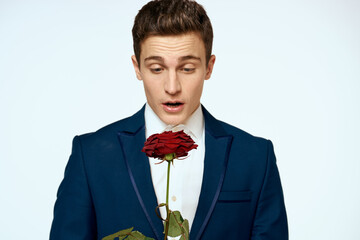 A man in a suit with a rose in his hands a gift date light background