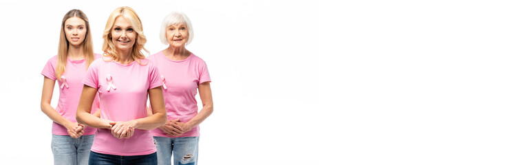 Panoramic shot of women with ribbons of breast cancer awareness looking at camera isolated on white