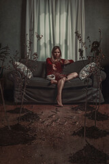 Bored blonde woman in quarantine, sitting on a couch, drinking red wine and throwing seeds at birds surrounding trees on the wooden floor of her living room