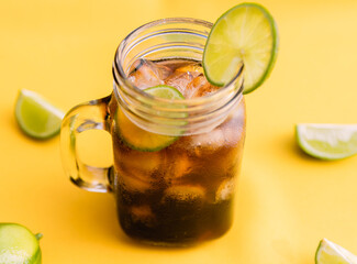 ice tea with slice of lemon in mason jar on bright yellow background. Top view composition slices of lemons