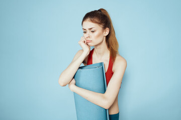 Sportive woman in red tank top mat for workout exercises lifestyle blue background