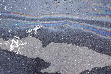 Obraz premium Colored oil stains in the car park, the color of the gasoline stain on the pavement road as a texture or background.