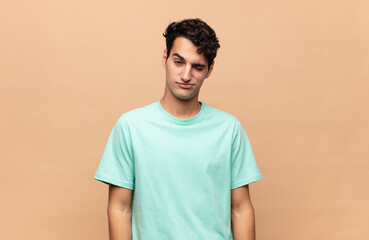 young handsome man looking happy and friendly, smiling and winking an eye at you with a positive...