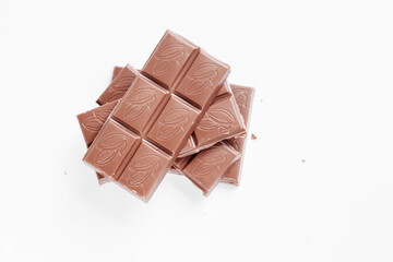 Milk chocolate pieces isolated on white background from top view, close up a chocolate bar isolated on white background