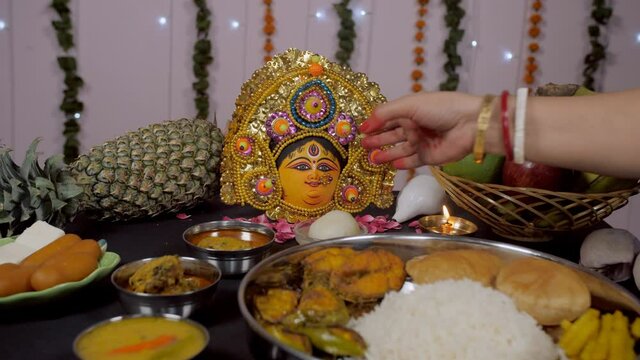 Religious Bengali woman keeping a Rosogolla as offering for Durga Puja. A married lady from West Bengal worshipping Ma Durga at home with a traditional Bengali Thali as Bhog/Prasad