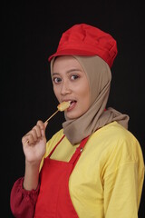 a woman trader in full uniform, is promoting her food in the form of egg satay. The woman bites and eats eggs to show off its delicacy.