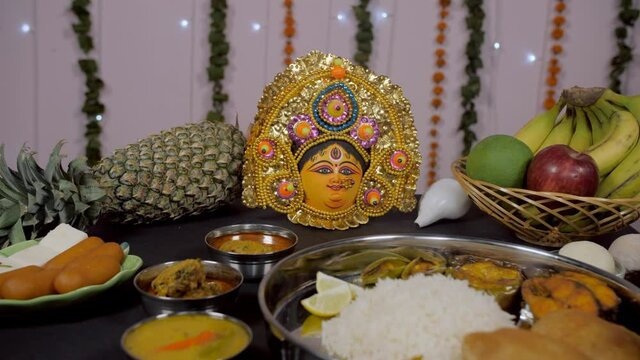 Traditional Bengali Thali/platter as offerings for Ma Durga rotating on a turntable. Close-up shot of a puja room with delicious Bhog Thali of rice  Lucchi  fries  Dal  fish  and a plate of sweets ...