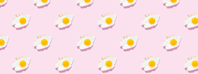 Fried eggs on a light pink background, pattern. Minimalism, top view. Breakfast concept, fried food.